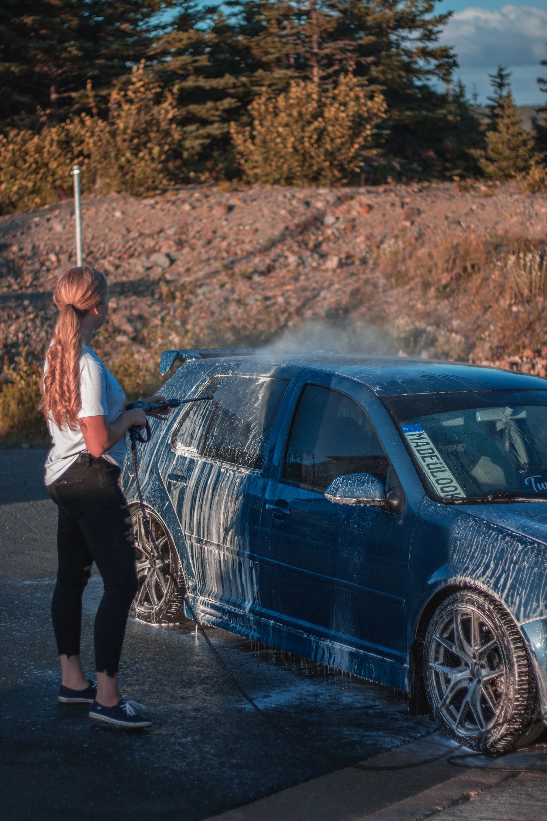 A blue vehicle being washed with foam outdoors